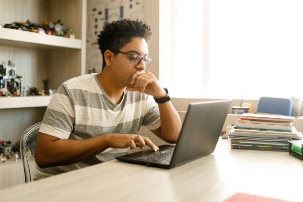 teenage boy studying with laptop at home - adolescente imagens e fotografias de stock