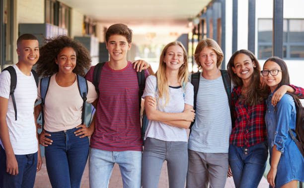 Teenage classmates standing in high school hallway Teenage classmates standing in high school hallway high school stock pictures, royalty-free photos & images