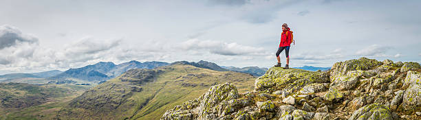 Teenage female hiker on rocky mountain summit overlooking peak panorama Teenage girl hiker standing on a mountain summit overlooking a panoramic vista of green valleys and rocky peaks high in the picturesque natural landscape of the Lake District National Park, Cumbria, UK. ProPhoto RGB profile for maximum color fidelity and gamut. cumbria stock pictures, royalty-free photos & images