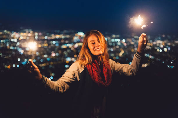 Teenage girl celebrating Christmas at rooftop terrace Young woman with burning sparklers at the rooftop new years eve girl stock pictures, royalty-free photos & images