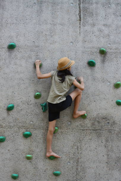 Teenage girl climbing the wall stock photo