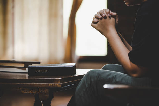Teenage girl hand with Bible praying stock photo