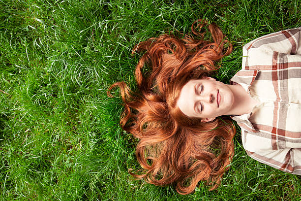 Teenage girl laying in grass Teenage girl laying in grass lying down stock pictures, royalty-free photos & images