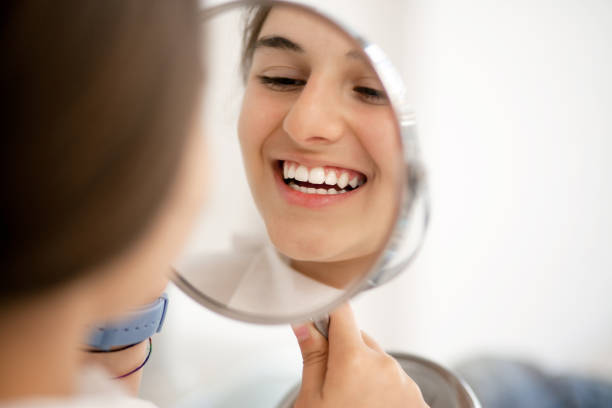 Teenage girl looking at her teeth in the mirror stock photo