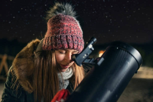 Teenage girl observing the winter night sky with telescope Teenage girl is using the astronomy telescope to observe the the stars at cold winter night.
Shot with Canon R5. astronomy telescope stock pictures, royalty-free photos & images