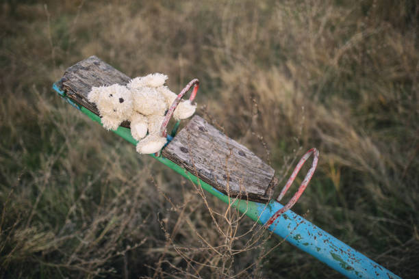 Teenage girl on playground with mobile phone Teddy bear left on seesaw on abandoned playground with rusty and broken equipment. broken doll 1 stock pictures, royalty-free photos & images