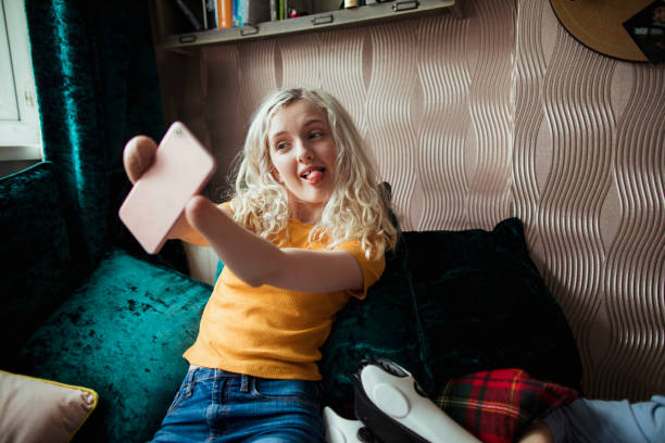 Teenage Girl Taking A Selfie A confident young girl sitting on her own, sticking her tongue out for a selfie. physical disability stock pictures, royalty-free photos & images