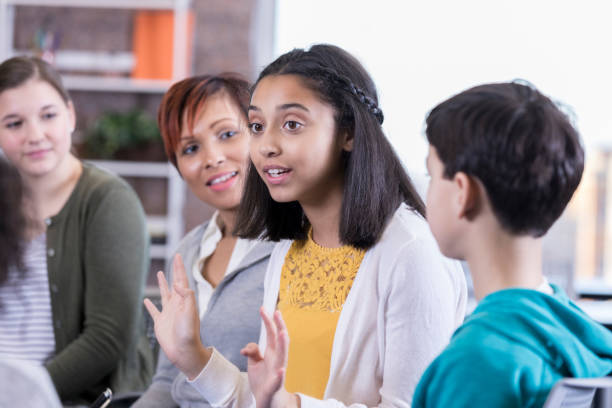Teenage girl talks in group therapy session African American teenage girl participates talks with other students and the school counselor during group therapy session. middle school teacher stock pictures, royalty-free photos & images