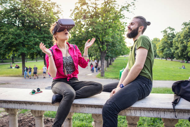 Teenage girl watching virtual reality in the park Teenage couple enjoying virtual reality on 3D glasses while relaxing in the park Portable DVD Player stock pictures, royalty-free photos & images