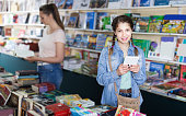 istock Teenage girl with screen tablet at books store 1320278907