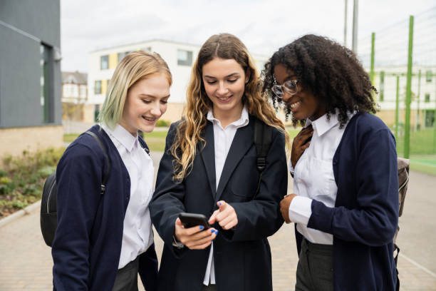 Teenage schoolgirls checking social media on smart phone stock photo