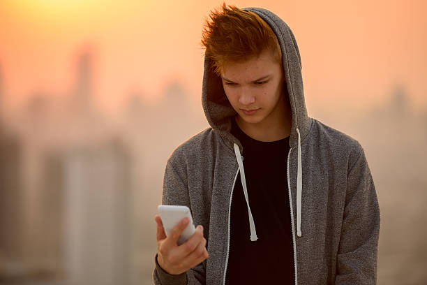 teenager boy outdoors using mobile phone - alleen één tienerjongen stockfoto's en -beelden