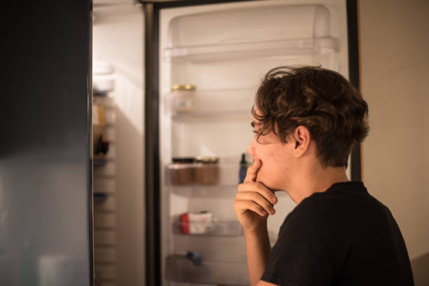 Teenager Boy Searching for Snacks in the Refrigerator stock photo