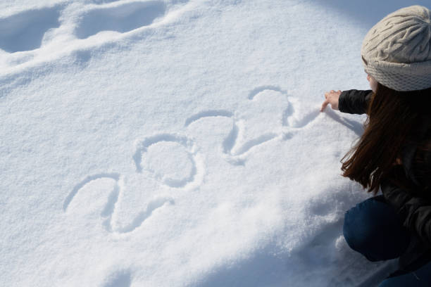Teenager draws New Year 2022 on snow stock photo