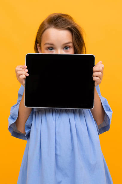fille d’adolescent dans une robe bleue avec une tablette avec une maquette d’écran - mockup vêtement enfants robe photos et images de collection