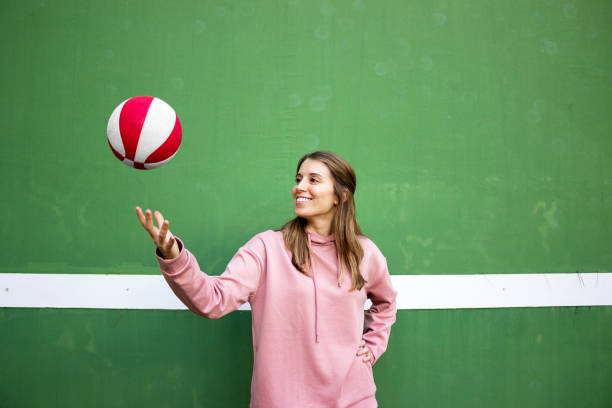 Teenager girl playing basketball over green wall stock photo