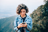 istock Teenager using cell phone outdoors 1365253345