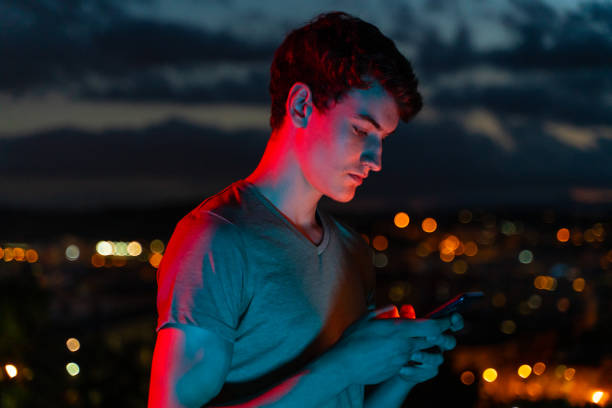 Teenager using smartphone at twilight stock photo