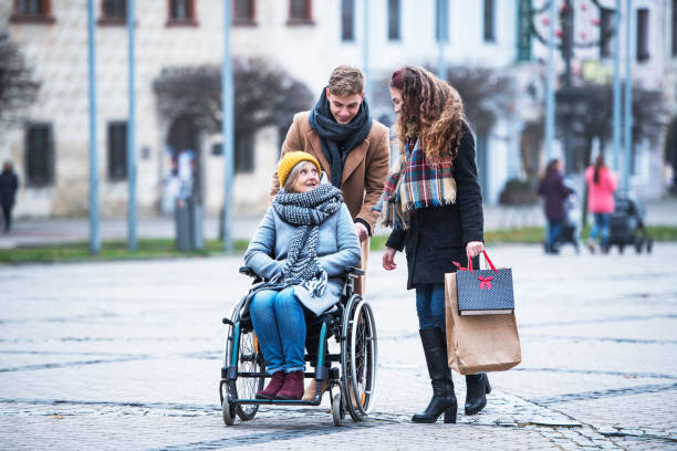 teenagers and senior grandmother in wheelchair walking down the street in winter. - wheelchair street happy imagens e fotografias de stock