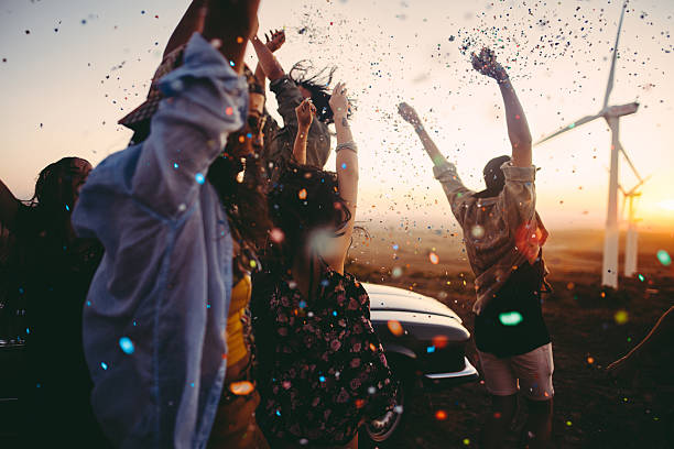 teenagers celebrating with colourful confetti on summer road tri - wind turbine sunset bildbanksfoton och bilder