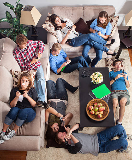 teens texting in a living room - alleen tieners stockfoto's en -beelden