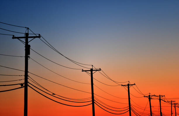 Telephone Poles at Sunset A line of telephone poles in front of a colorful sky at sunset. electricity pylon stock pictures, royalty-free photos & images