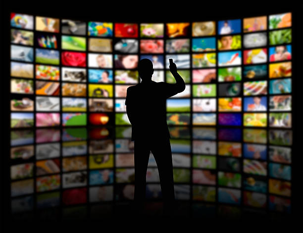 Television production concept. TV movie panels Back view of a young man watching a big TV panel led light photos stock pictures, royalty-free photos & images