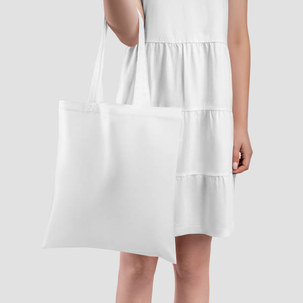 Template of a white reusable totebag on a girl in a sundress, handbag close-up, for design, pattern. stock photo