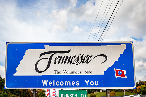 A Tennessee Welcomes You sign on the highway marking the state border with Tennessee.