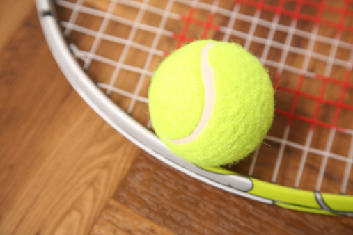 Sports backgrounds.  Tennis racket and ball on unique wooden boards background. Selective focus on boards. 