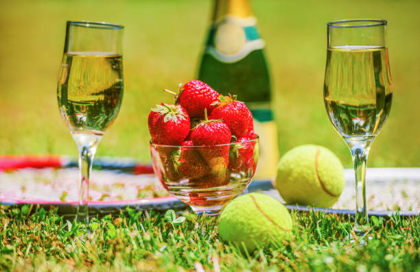 tenis oyunu. çilek, şampanya ve tenis topları yeşil çim üzerinde raketler ile. spor, rekreasyon konsepti - wimbledon tennis stok fotoğraflar ve resimler
