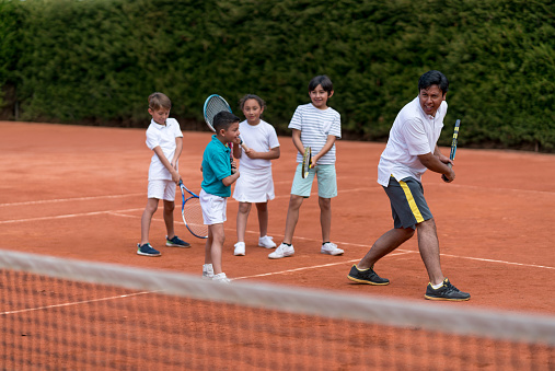Tennis Teacher Teaching A Group Of Kids How To Play Tennis