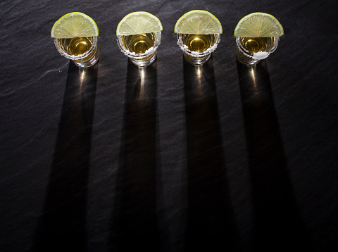 tequila-shots-with-deep-long-shadows-on-black-background-picture-id671961504