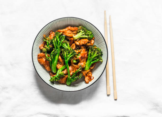 Teriyaki stir fry chicken with broccoli and noodles on light background, top view. Asian style food stock photo