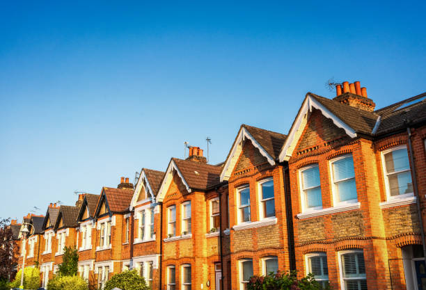 A long row of traditional Victorian terraced houses in Ealing, West London, below a clear blue summer sky.