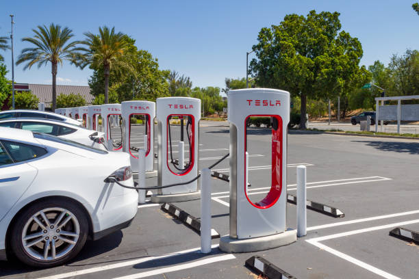 Tesla charging at Tesla Supercharger Station at the Brea Mall Brea, CA, USA – August 1, 2021: A white Tesla charging at Tesla Supercharger Station at the Brea Mall in Brea, California. tesla motors stock pictures, royalty-free photos & images