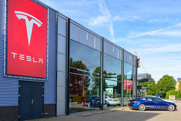 Tesla Motors dealership with a Tesla Model S electric car Duiven, The Netherlands - September 10, 2015: Blue and white Tesla Model S full electric luxury car parked outside a dealership. The Tesla Model S is a full-sized plug-in electric five-door, luxury liftback, produced by the American automotive company Tesla Motors. tesla motors stock pictures, royalty-free photos & images