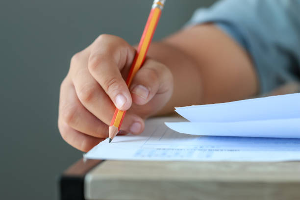 test exam for education in school concept : University student holding pencil notes paper on answer sheet at lecture chair for taking exams in examination classroom. Assessment learning in class ideas stock photo