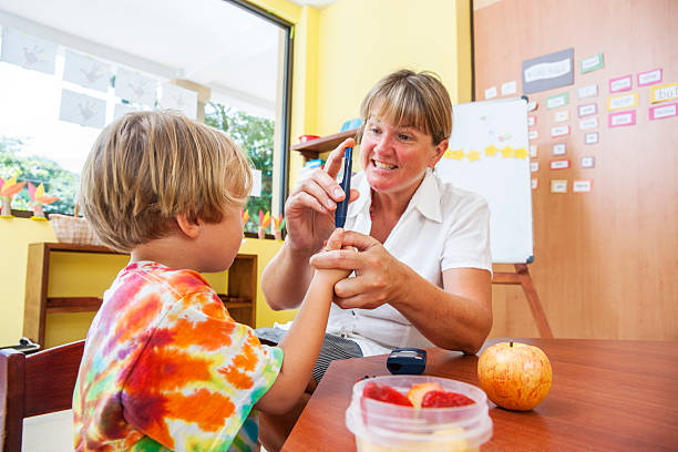 Testing blood sugar at school A nurse shows a diabetic child how to test his blood. in a classroom in school. non us film location stock pictures, royalty-free photos & images