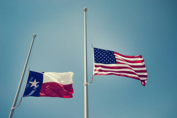 Texas and the United States flags at half-staff The state flag of Texas and the United States flag flying at half-mast or half-staff on a flagpole. Blue sky background with copy space. Vintage filter effects. flag at half staff stock pictures, royalty-free photos & images