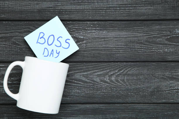 Text Boss Day on sticker and white cup on black wooden background stock photo