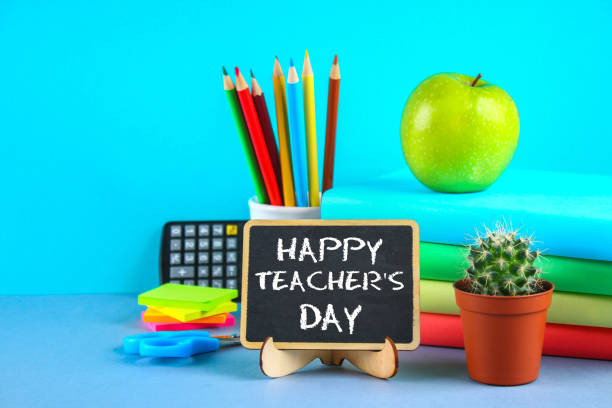 Text chalk on a chalkboard: Happy Teacher's Day. School supplies, office, books, apple. stock photo