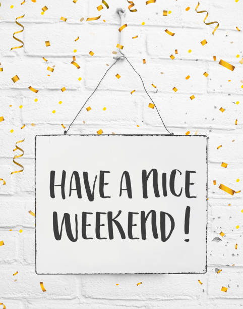Text have a nice weekend white sign banner board with golden confetti on white brick background stock photo