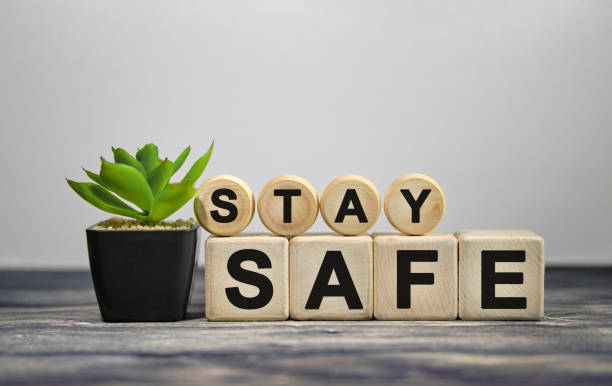 stay safe - text auf holzwürfeln, grüne pflanze im schwarzen topf auf holzhintergrund - sicherheitsmaßnahme stock-fotos und bilder