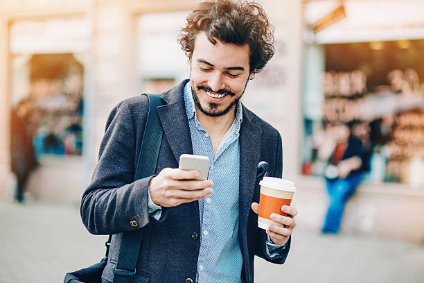 texting on the street - walking with coffee stockfoto's en -beelden