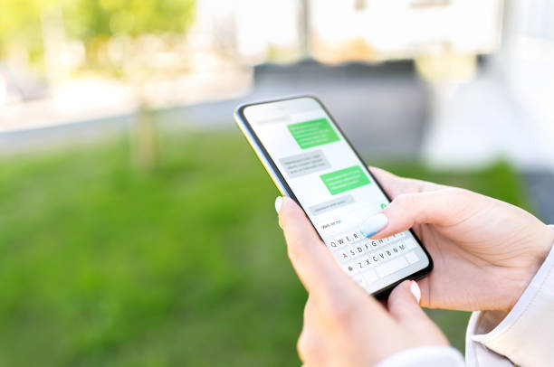 市内の屋外公園で電話でsmsをテキストメッセージ。携帯電話でテキストメッセージを送信する女性。インスタントメッセージングアプリでチャット。スマートフォンを使用する人。 - テキストメッセージ ストックフォトと画像