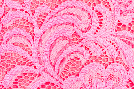 Texture of pink openwork fabric with embroidery.