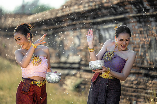 Thai girls splashing water during festival Songkran festival, Beautiful Thai woman wearing thai traditional clothing in songkran festival culture of Thailand.