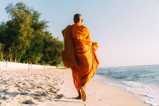 Thai monk walking on beach in Thailand stock photo