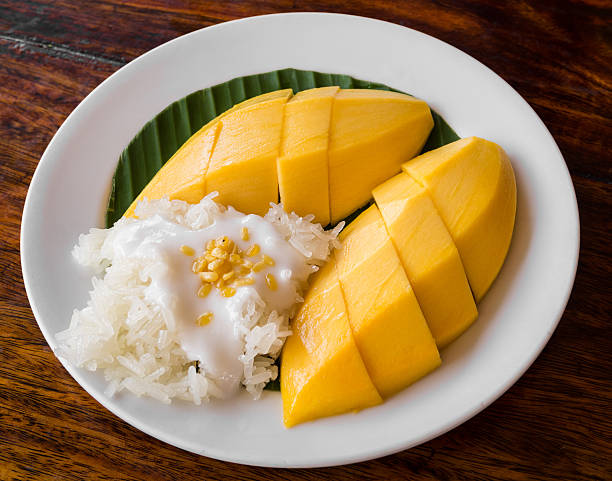 thai style tropical dessert, glutinous rice eat with mangoes - kleverig stockfoto's en -beelden